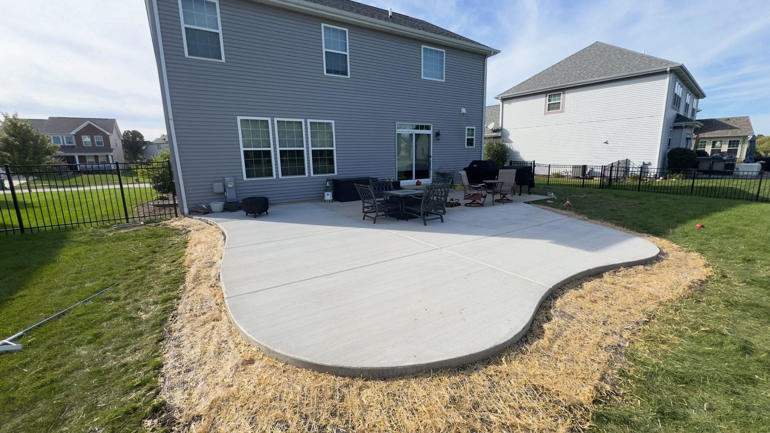 Free-form curved patio behind a gray home